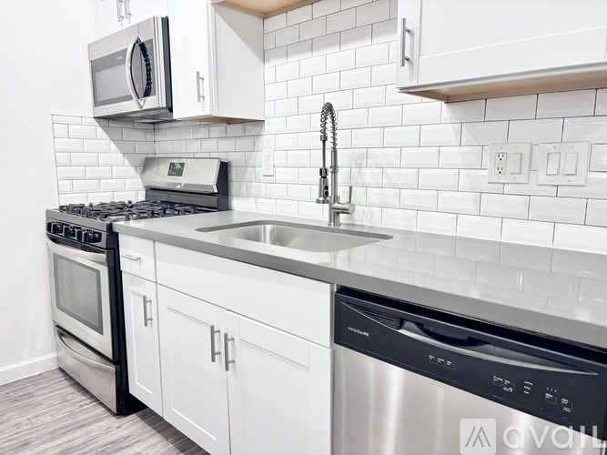 A modern kitchen with white cabinets and stainless steel appliances.