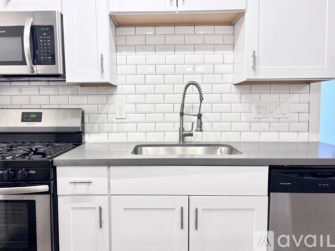 A modern kitchen with white cabinets and a black stove top oven.