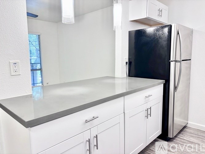 A black refrigerator is in a kitchen with white cabinets.