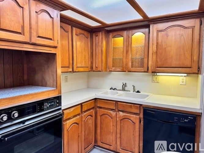 A kitchen with wooden cabinets and a black dishwasher.
