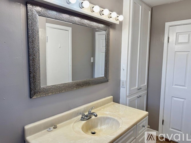 A bathroom with a sink, mirror, and lighted vanity mirror.