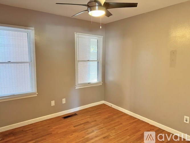 A room with a ceiling fan and two windows.