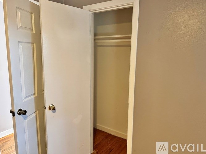 A white door is open to a room with a wooden floor.