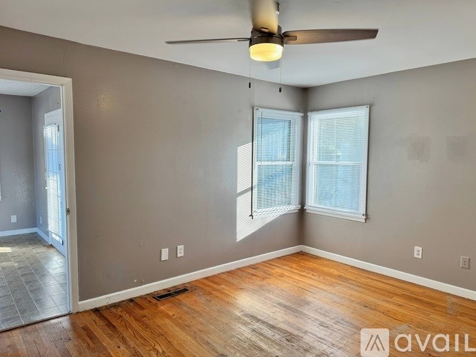A room with a ceiling fan and two windows.
