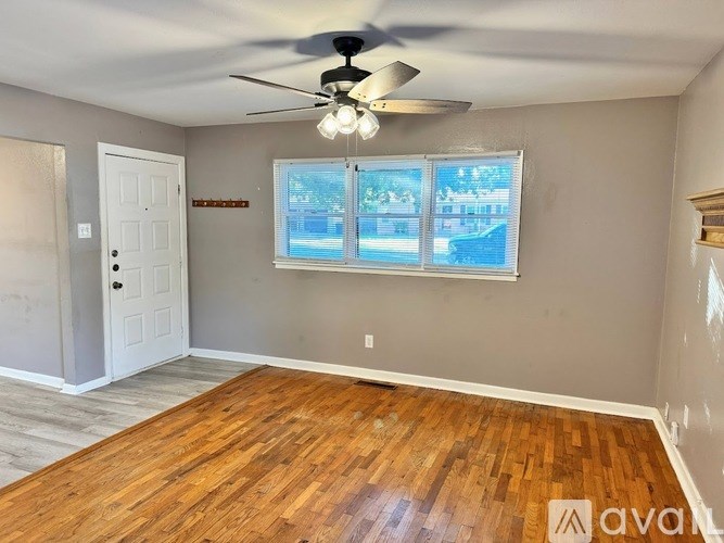 A room with a ceiling fan and wooden flooring.
