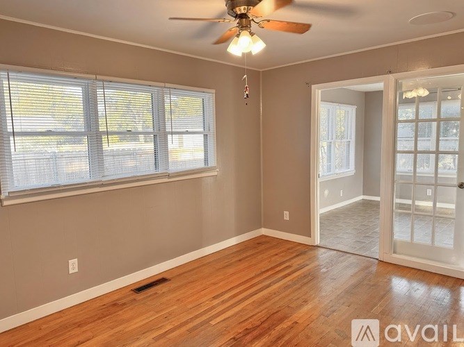 A room with a ceiling fan and sliding glass doors.