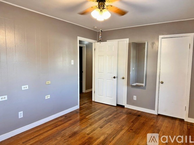 A room with a ceiling fan and three doors.