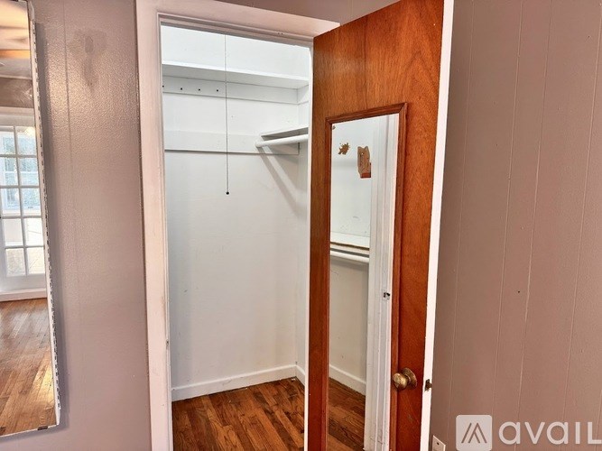 A room with a wooden door and a white wall.