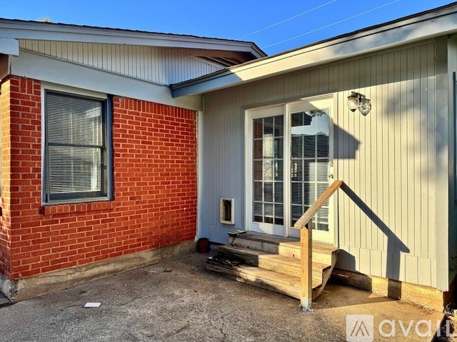 A house with a red brick wall and a grey siding wall with a small porch.
