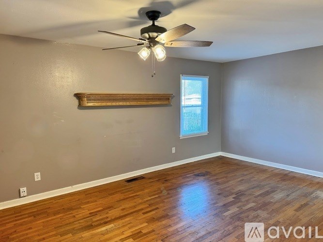 A room with a ceiling fan and wooden flooring.