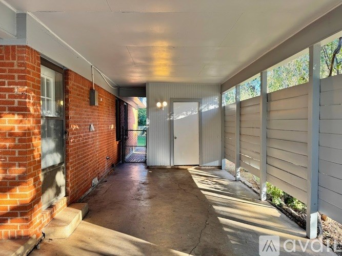 A covered walkway with a brick wall on one side and a metal gate on the other.