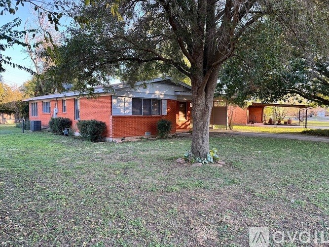 A red brick house with a tree in front.
