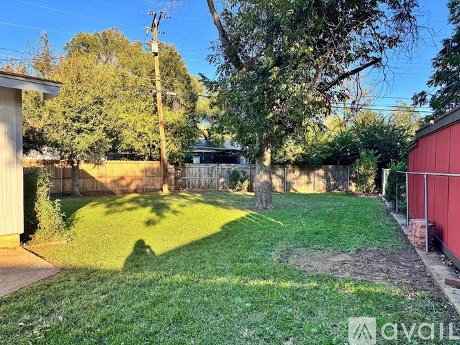 A backyard with a green lawn and a red shed.
