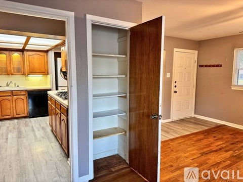 A kitchen with wooden cabinets and a refrigerator with an open door leading to a hallway.