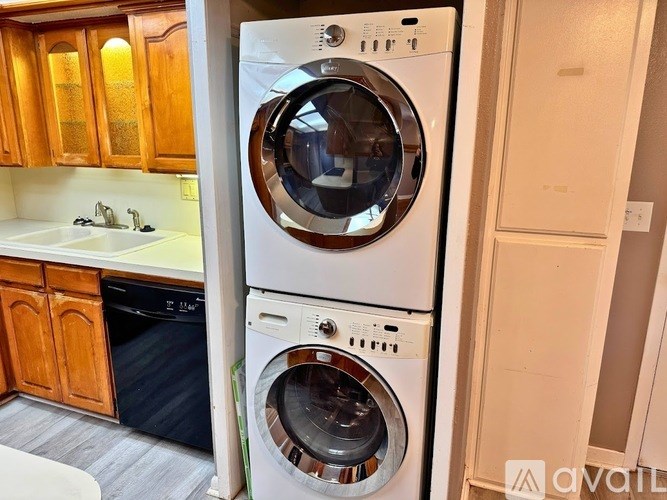 A white washing machine and dryer stacked on top of each other in a kitchen.