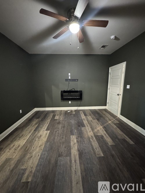 A room with a ceiling fan and wooden flooring.