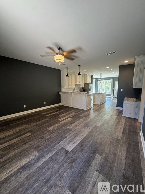 A room with a fan and wooden flooring.