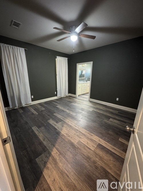 A room with a ceiling fan and wooden flooring.