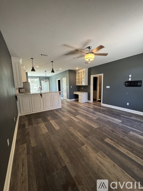 A room with a ceiling fan and wooden flooring.