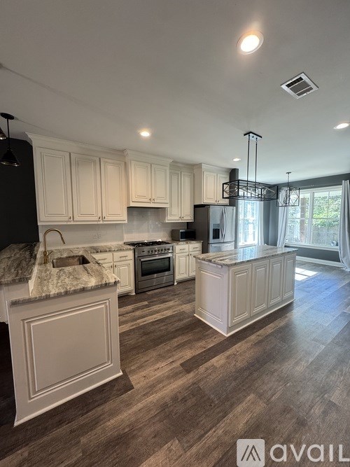 A kitchen with white cabinets and a wooden floor.