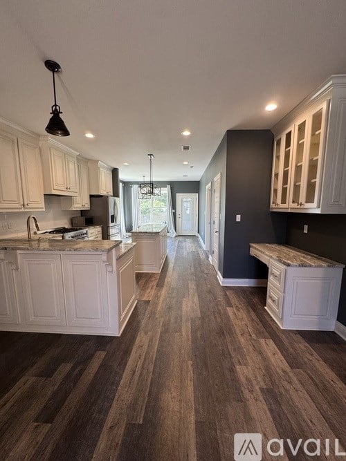 A kitchen with white cabinets and a wooden floor.