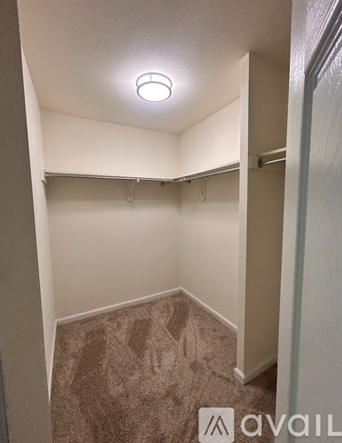 A small, empty room with a carpeted floor and a single light fixture on the ceiling.