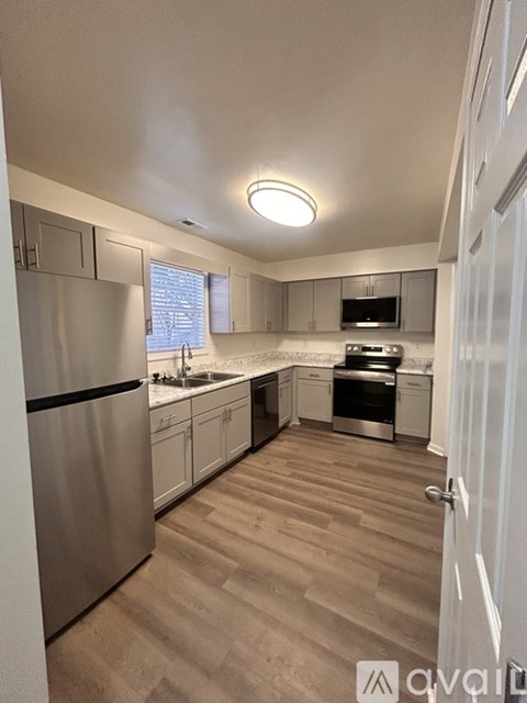 A kitchen with a refrigerator, sink, and stove.
