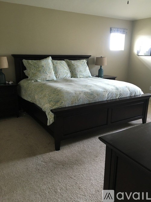 A bedroom with a large bed and two lamps.