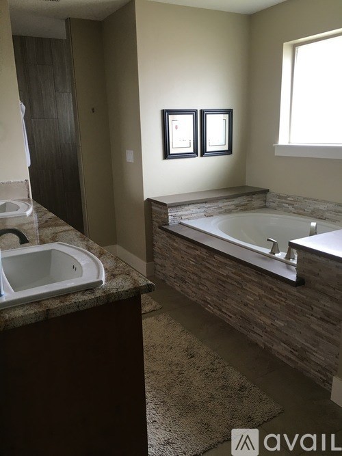 A bathroom with a tub, sink, and pictures on the wall.