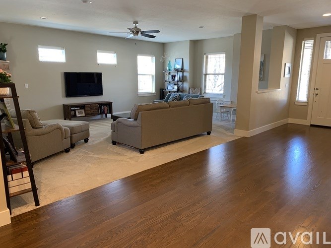 A living room with a television, couches, and a wooden floor.