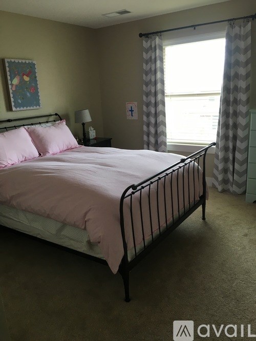 A bedroom with a bed, nightstand, and window.