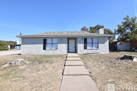 A house with a grey roof and white walls is for sale.