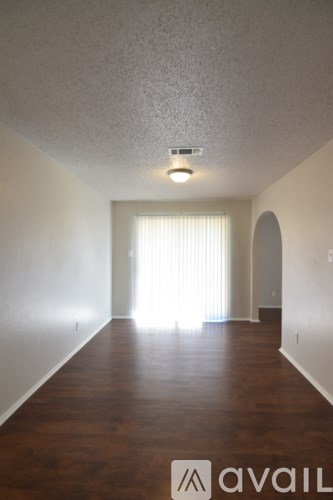 A room with wooden floors and a window with white curtains.