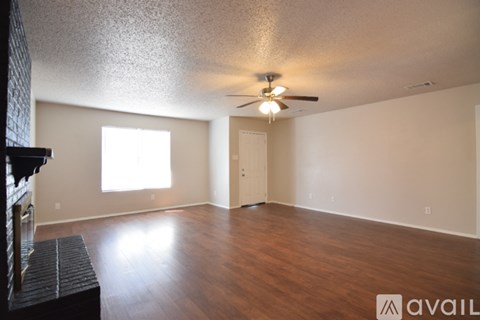 A spacious room with wood flooring and a ceiling fan.