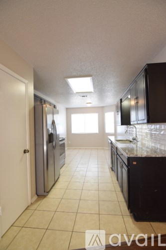 A kitchen with black cabinets and a tiled floor.
