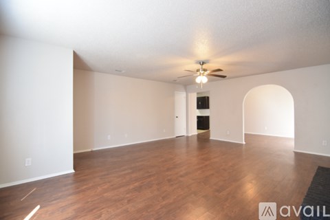 A spacious room with wooden floors and a ceiling fan.