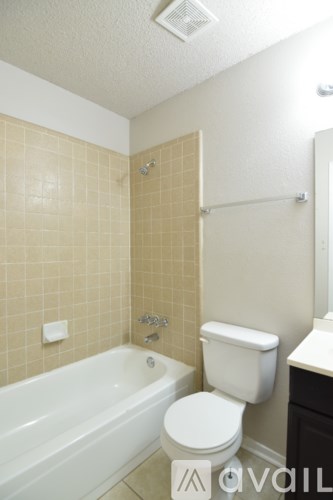 A white toilet sits next to a bathtub in a bathroom.