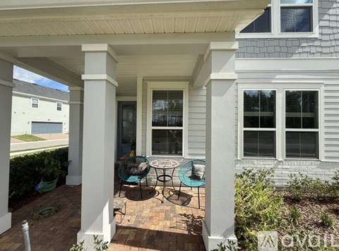 A patio with a table and chairs is covered by a roof.