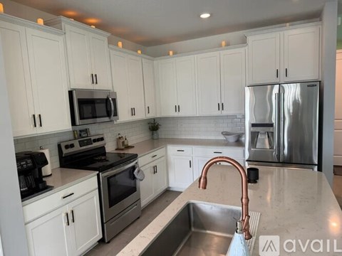 A kitchen with white cabinets and a stainless steel refrigerator.