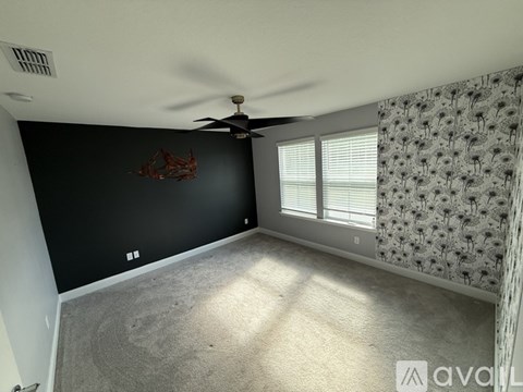 A room with a ceiling fan and a wall hanging.