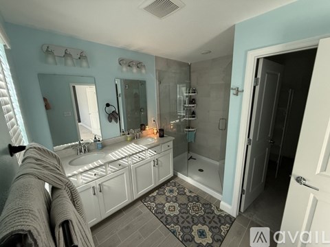 A bathroom with a sink, mirror, and shower.