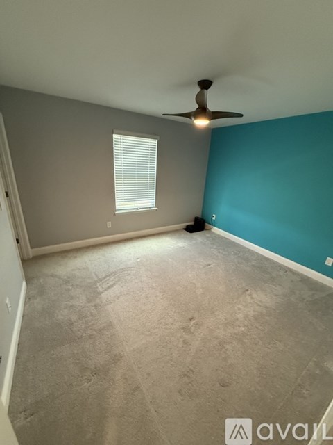A room with a ceiling fan and a window with blinds.