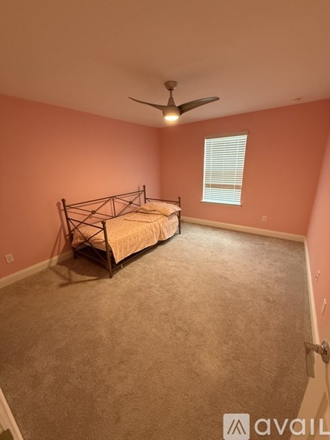 A bedroom with a bed, carpet, and a ceiling fan.