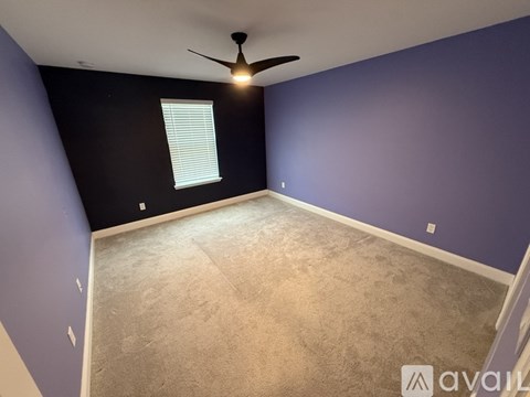 A room with a ceiling fan and a window with blinds.