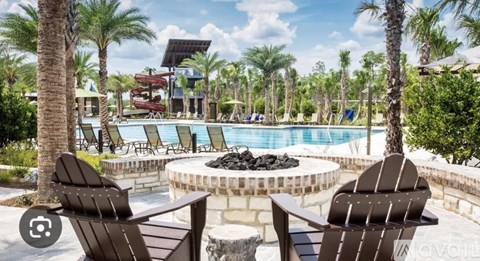 Two chairs are facing a pool with a waterfall and palm trees.