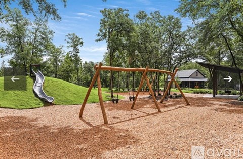 A wooden swing set in a playground with a green slide.