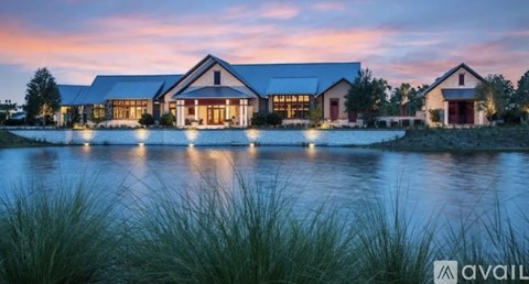 A house with a large front yard and a pond in front of it.