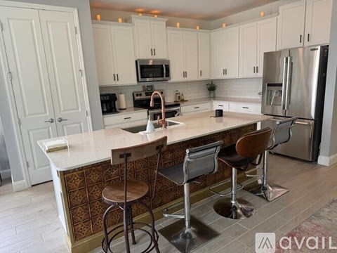 A kitchen with a white countertop and bar stools.