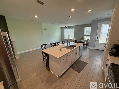 A kitchen with a white island and a refrigerator on the left.