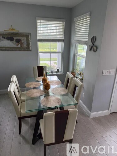 A glass dining table with chairs and a painting on the wall.